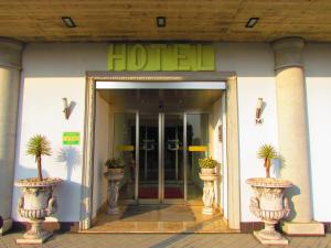 a hotel entrance with potted plants in front of it at Hotel Emily Fiera in Lainate