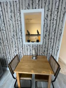 a table with chairs and a mirror on a wall at Alpine Apartments - 2 in Blairgowrie +1 photo