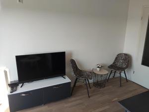 ein Wohnzimmer mit 2 Stühlen und einem Flachbild-TV in der Unterkunft Apartmani Sarah 2 Tuzla in Tuzla