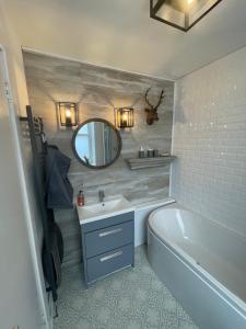 a bathroom with a tub and a sink and a mirror at Alpine Apartments - 2 in Blairgowrie