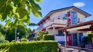 a house with a red window and bushes at Residence Al Lago in Castiglione del Lago