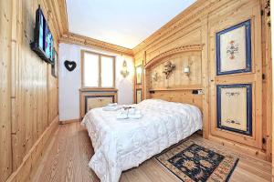 een slaapkamer met een wit bed in een kamer met houten wanden bij Luxury Apt Dolomites 2 in Pinzolo