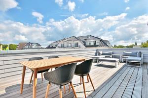 a deck with a wooden table and chairs on a roof at Ostsee Suite 2 - Penthouse in Niendorf