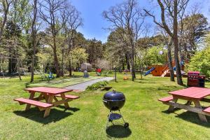una parrilla y mesas de picnic en un parque en Self-Sufficient Cottages at Even'tide Resort, en Wellfleet
