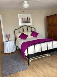 The Bell Inn في تشلتنهام: غرفة نوم مع سرير بملاءات ووسائد أرجوانية