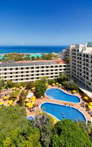 eine Luftansicht eines Resorts mit Pools und Sonnenschirmen in der Unterkunft H10 Tenerife Playa in Puerto de la Cruz