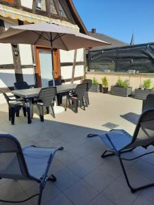 eine Terrasse mit Tisch, Stühlen und Sonnenschirm in der Unterkunft Au bonheur des hirondelles in Kirrwiller + 9 Fotos