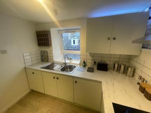uma cozinha com armários brancos, um lavatório e uma janela em Alpine Apartments - 1 em Blairgowrie