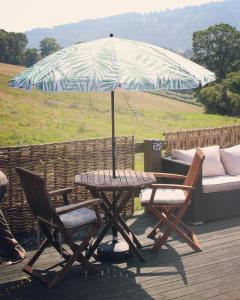 a table and two chairs and an umbrella on a deck at Sunbank Yurt in Llangollen