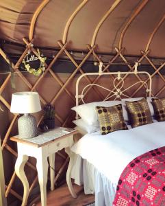 a bedroom with a bed and a table with a lamp at Sunbank Yurt in Llangollen