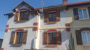 un edificio con finestre con persiane marroni di Maison, jardin, barbecue et vélo classé 3 étoiles a Dives-sur-Mer