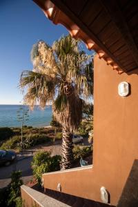 a palm tree next to a building with a view of the ocean at Appartamento Sole e Mare in Santa Margherita di Pula