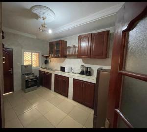 La cuisine est équipée de placards en bois et d'un four avec plaques de cuisson. dans l'établissement Appartement cosy goldy bonapriso, à Douala