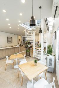 a restaurant with wooden tables and white chairs at Connect Hostel in Chiang Rai