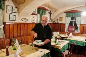 Un uomo anziano che tiene un piatto in un ristorante di Landhaus Gritschacher a Sankt Peter in Holz