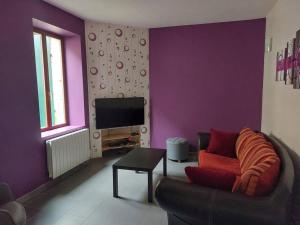 a purple living room with a couch and a tv at La Ribote in Sancerre