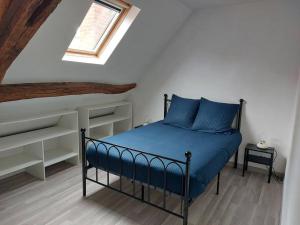 een slaapkamer met een bed met blauwe lakens en een raam bij La Ribote in Sancerre