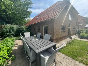 a wooden table and chairs in a yard with a house at Leuk boerderijtje op prachtige plek, nabij natuurgebied in Ruurlo