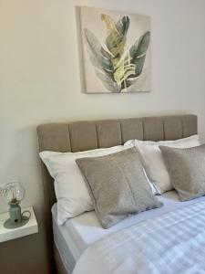 łóżko z białymi poduszkami i zdjęciem na ścianie w obiekcie Apartments Fortuna w Biogradzie na Moru