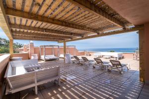 a patio with benches and tables and a view of the ocean at Hotel El Cortijo de Zahara in Zahara de los Atunes
