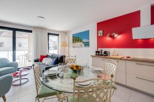 Il dispose d'une cuisine et d'un salon avec une table et des chaises en verre. dans l'établissement Emergence - Appartement 1 chambre 2-4 pers Garage et Terrasse, à Annecy