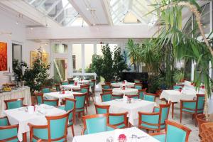 a restaurant with white tables and chairs and plants at Altstadt Hotel Mosser Villach mit Parkplatz in Villach