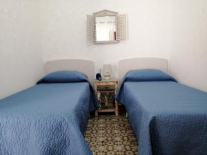 2 łóżka w pokoju z niebieskimi kołdrami w obiekcie CASA FRANCESCA w mieście Gonnesa