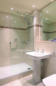 a bathroom with a sink and a shower with a glass door at Macdonald Kilhey Court Hotel in Wigan