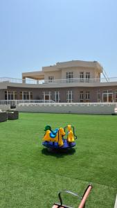 un jouet pour enfants dans l'herbe devant un bâtiment dans l'établissement Ocean Chalet, à Salalah