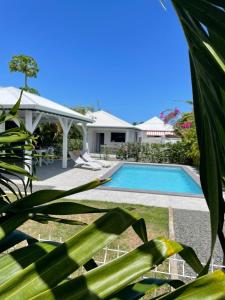 a villa with a swimming pool and a house at Gîtes de Corneille, Bungalow Little Banania in Le Moule