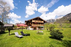 una casa en un campo con dos sillas y una sombrilla en Landhaus Berktold, en Oberstdorf