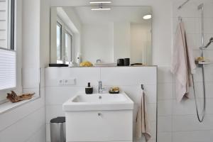 a white bathroom with a sink and a shower at Strandperle Ostsee Suite 3 in Niendorf +15 photos