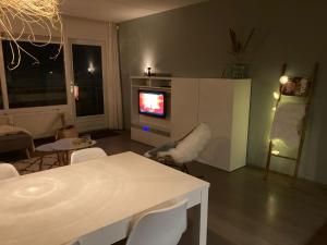 sala de estar con TV, mesa y sillas en CallantsDuinzicht, Beachappartement 24, en Callantsoog