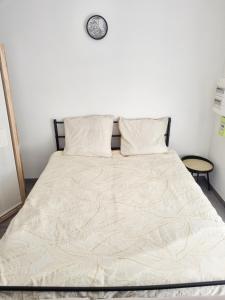 uma cama num quarto com um relógio na parede em Logement chaleureux 2 personnes em Saint-Gaudens