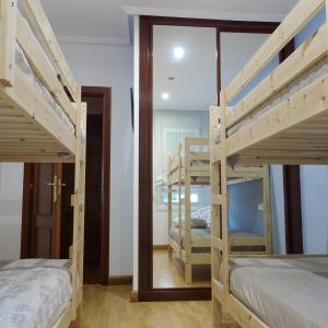 a room with two bunk beds and a mirror at El Gato Gordo - bike & surf house in Cudillero