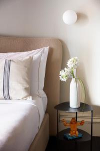 un letto con un tavolo e un vaso di fiori sopra di HOTEL VITE - By Naman Hotellerie a Roma
