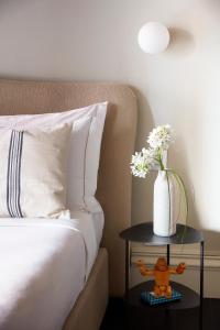 a white vase with flowers sitting on a bed at HOTEL VITE - By Naman Hotellerie in Rome
