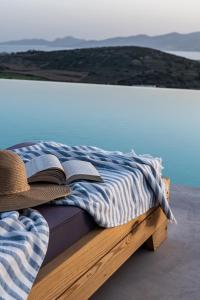 a bed with a hat and a book on it at Sun House Paros in Kampos Paros