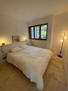 een slaapkamer met een groot wit bed en een raam bij Cosy T3 proche plage. Fibre. Clim in Saint-Mandrier-sur-Mer