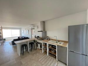 eine Küche mit einem Kühlschrank aus Edelstahl und einem Tisch in der Unterkunft Cosy T3 proche plage. Fibre. Clim in Saint-Mandrier-sur-Mer