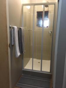 a shower with a glass door in a bathroom at Ncotshane BnB in Pongola