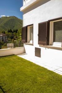 un edificio bianco con finestre e erba verde di Bed and Breakfast La Villa a Fiastra