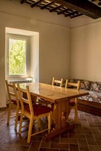 une table à manger en bois avec des chaises et une fenêtre dans l'établissement Bed and Breakfast La Villa, à Fiastra