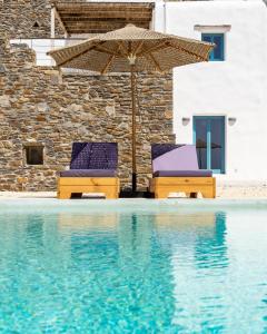 twee stoelen en een parasol naast een zwembad bij Sun House Paros in Kampos Paros