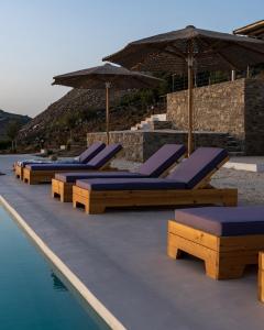 a row of lounge chairs and umbrellas on a swimming pool at Sun House Paros in Kampos Paros
