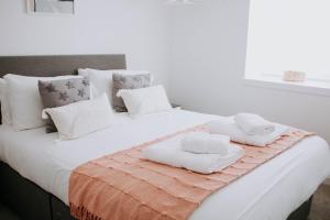 uma cama branca com almofadas brancas e toalhas em The Bailey - Troon - Coorie Doon Stays em Troon