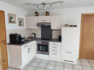 a kitchen with white cabinets and a stove top oven at Ferienwohnung am Trillenbühl in Salem