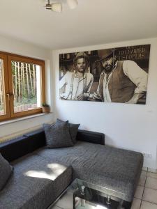 a living room with a couch and a poster of two men at Ferienwohnung am Trillenbühl in Salem