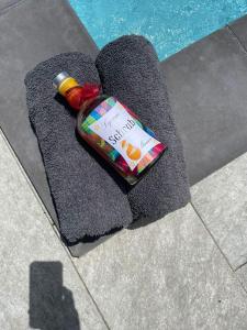 eine Flasche auf einem Handtuch neben einem Swimmingpool in der Unterkunft Gîtes de Corneille, Bungalow Sweet Mango in Le Moule