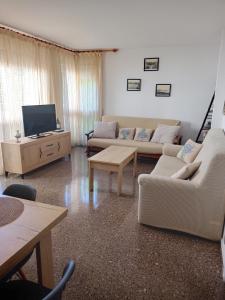 sala de estar con 2 sofás y TV en Apartament Edifici Simbat a 150m de la platja, en Palamós